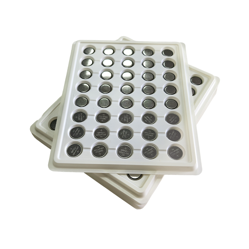 How can improvements in the packaging process of button batteries reduce their self-discharge rate?